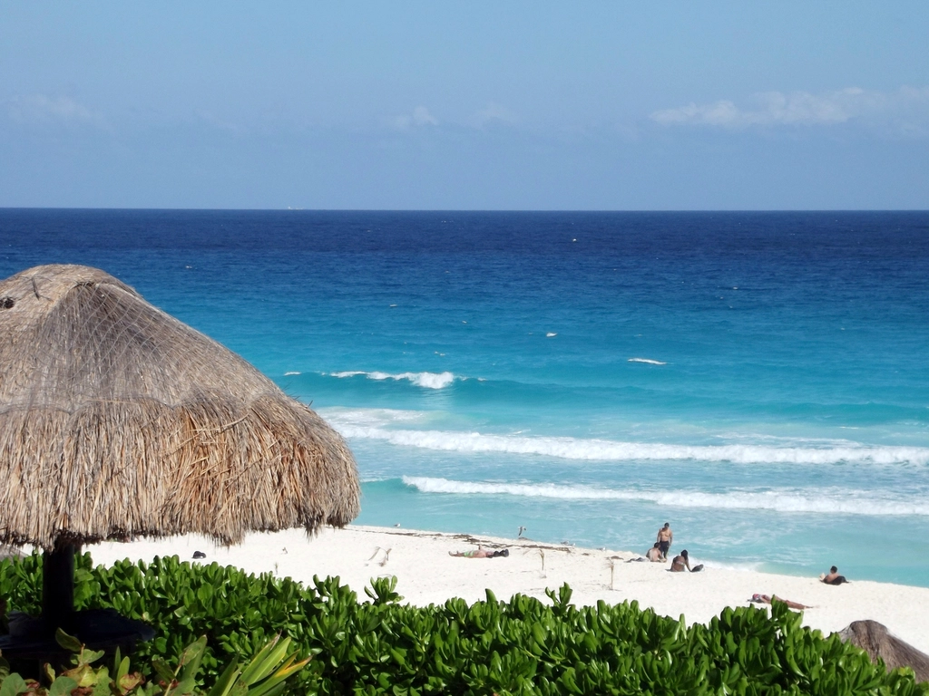 A palm-thatched shade on a white beach by the turquoise Caribbean sea